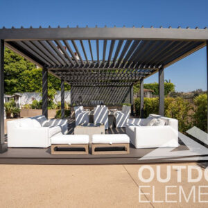 Black aluminum louvered pergola shading white outdoor sofa seating and dining area on backyard deck