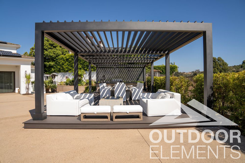 Black aluminum louvered pergola shading white outdoor sofa seating and dining area on backyard deck