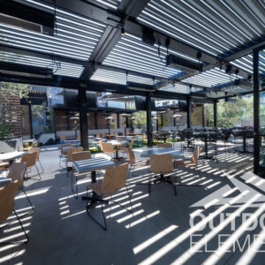 Louvered pergola shading outdoor restaurant patio seating with woven bistro chairs