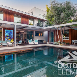 Modern wood-clad home with pergola-covered patio and reflecting pool at dusk