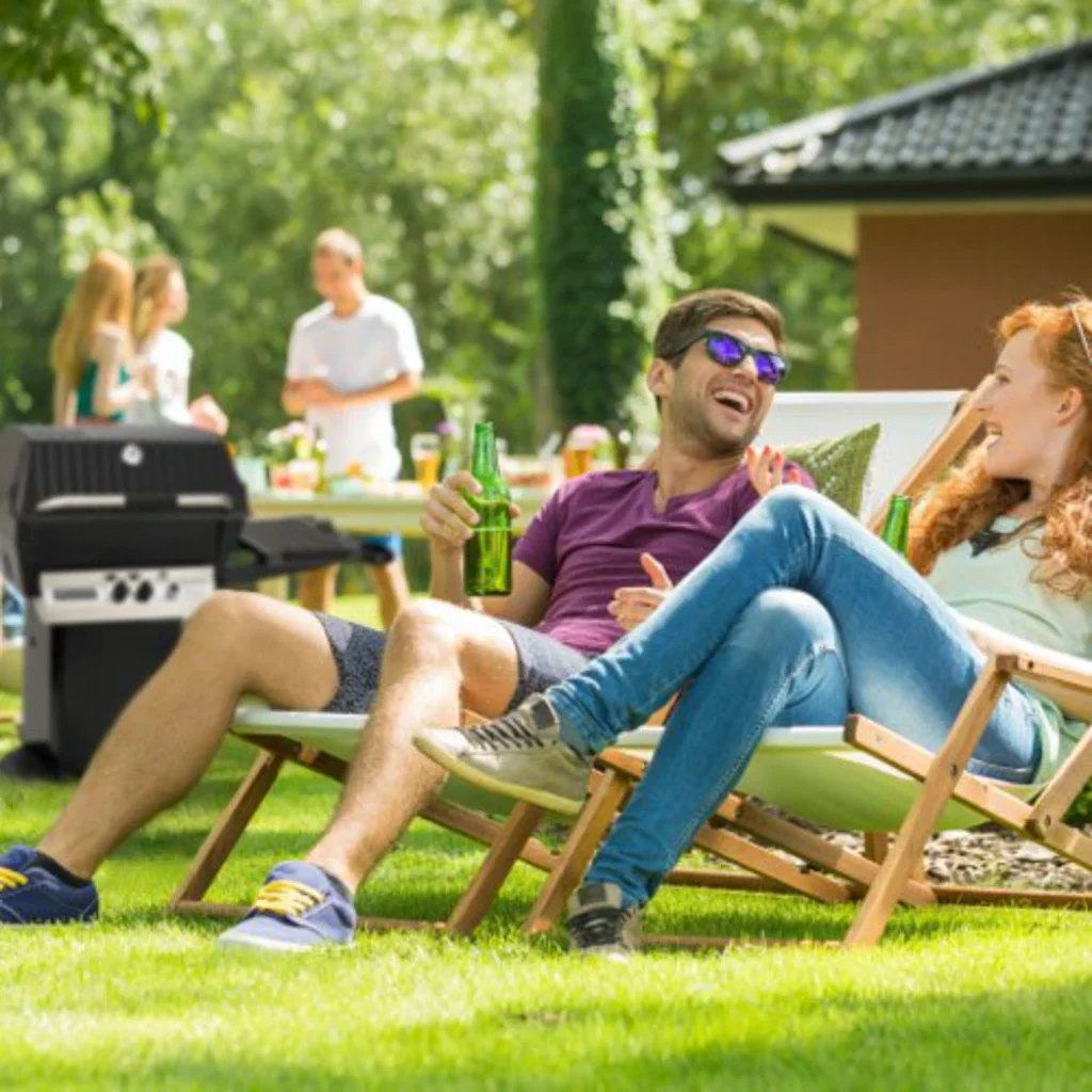 Friends relaxing in folding chairs at a backyard barbecue gathering on the lawn
