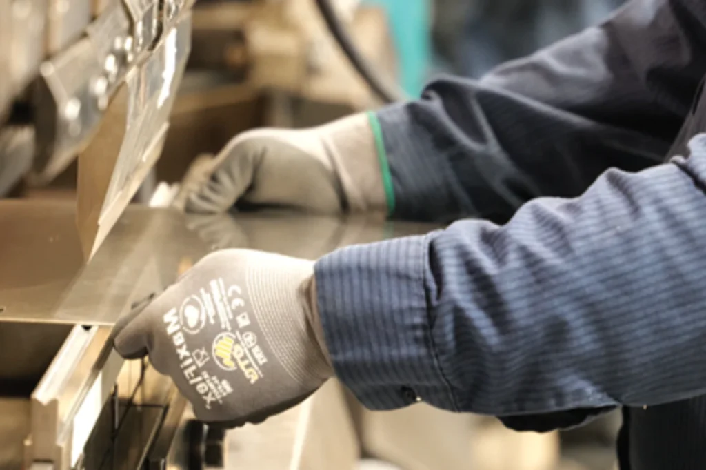 Worker in protective gloves operating industrial machinery equipment on a factory production line