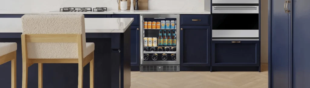 Built-in stainless steel beverage refrigerator stocked with cans and bottles in navy kitchen cabinetry