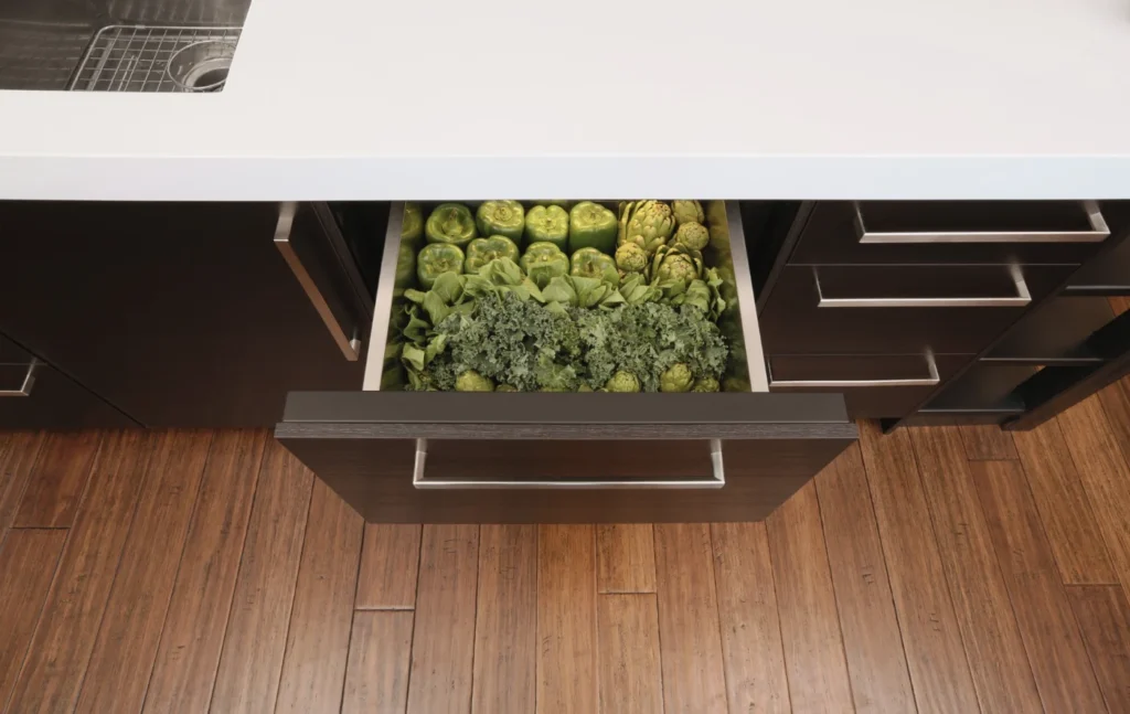Built-in undercounter refrigerator drawer stocked with fresh artichokes in a kitchen island