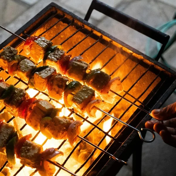 Grilled paneer and vegetable skewers cooking over open flame on outdoor grill