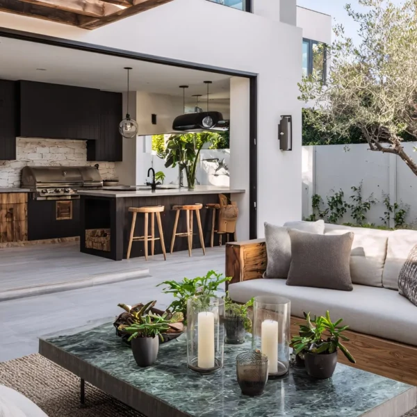 Indoor-outdoor living space with black kitchen island, stone pizza oven, and patio lounge seating