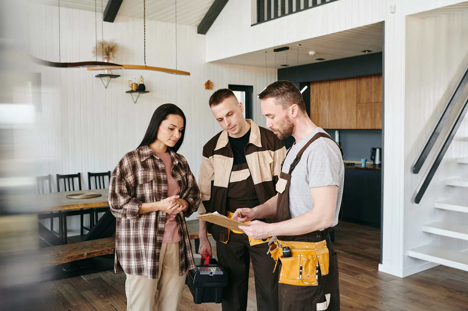 Two contractors reviewing renovation checklist with homeowner in modern kitchen