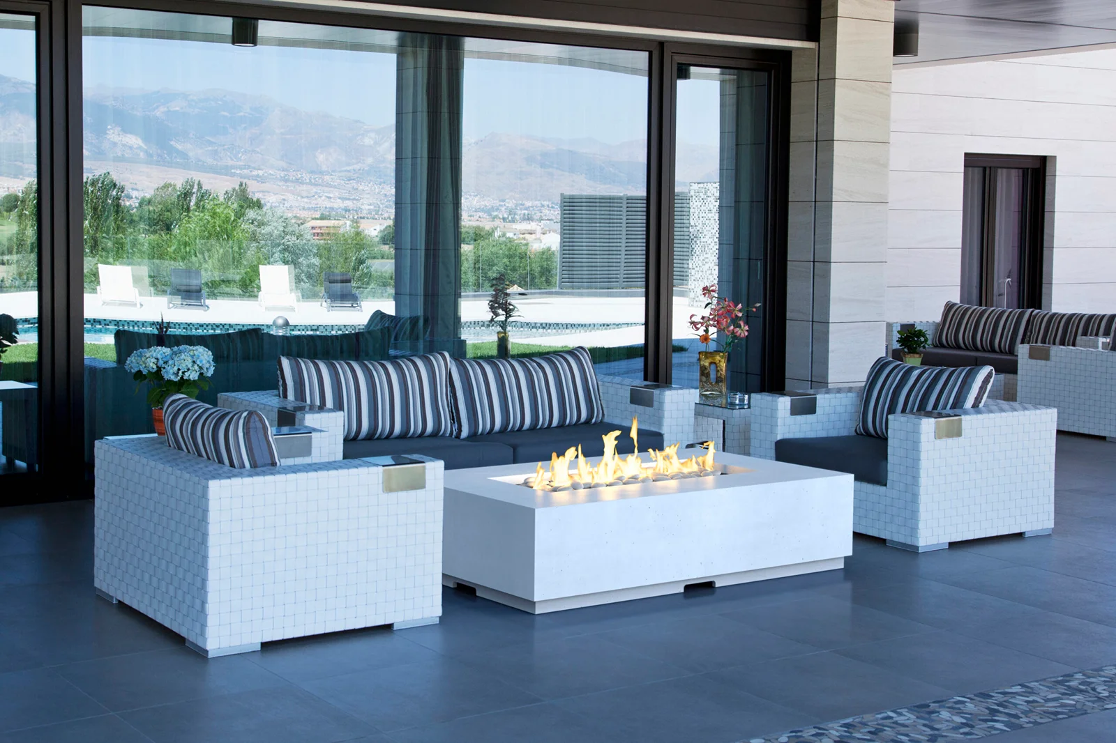 White woven rectangular fire table with striped cushioned seating overlooking mountain view