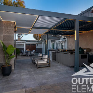 Louvered pergola with LED edge lighting over outdoor kitchen and lounge seating at dusk