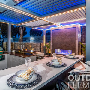 Pergola with blue and amber LED lighting over dining table and stone fireplace at night