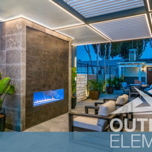 Linear gas fireplace built into stone accent wall on pergola-covered patio at night