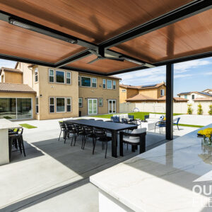 Wood-paneled pergola over outdoor dining table and kitchen island in backyard patio