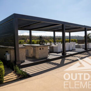 Black louvered pergola covering outdoor kitchen and lounge seating with hillside view