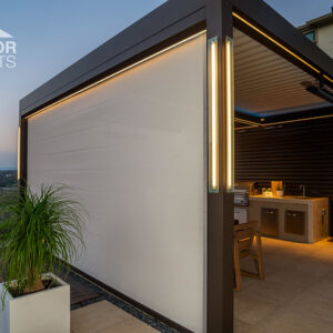 Pergola with retractable privacy screen and LED lighting over rooftop outdoor kitchen