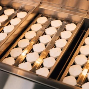 Ceramic briquettes lining a stainless steel gas grill burner tray